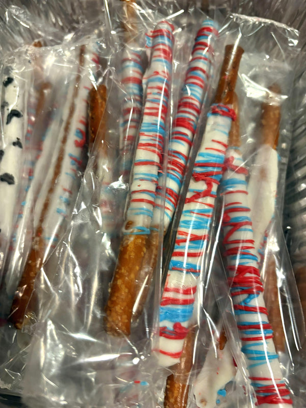 White chocolate-covered pretzel rods with red and blue drizzle by P&C Baking